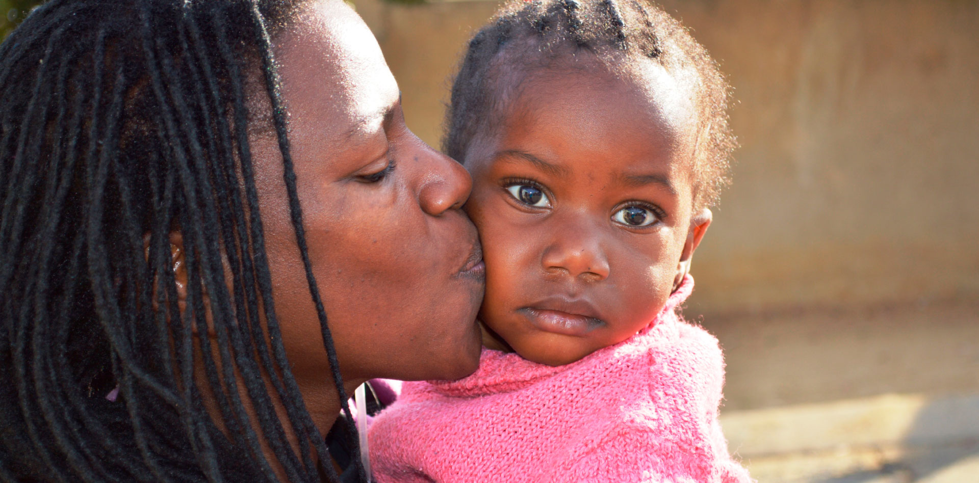 A mother kissing her daughter on the cheek.