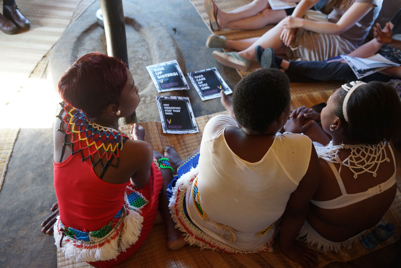 Women sitting on the floor with pamphlets about birth control and safe sex.